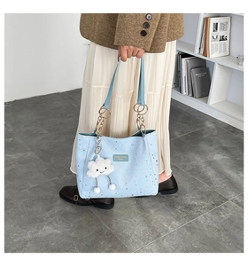 Detail of light blue tote bag with silver star patterns and cloud charm accessory