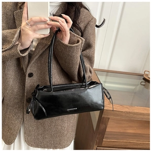 Détail d'un sac bandoulière en cuir verni noir brillant avec nœuds et logo blanc