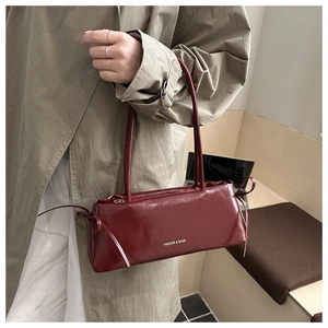 Dettaglio della borsa bordeaux lucida sottobraccio con fiocco e scritte alla moda