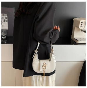 Detail of white PU leather hobo bag featuring gold interlocking logo and metallic tassels