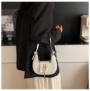 Detail of white PU leather hobo bag featuring gold metal logo and tassel decoration