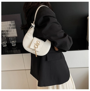 Close-up of white crescent underarm bag with gold braided logo and fringe details