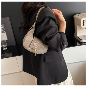 Detail of vintage textured PU leather crossbody bag with tassel and gold metal hardware