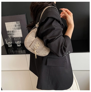 Detailed side view of vintage coffee PU leather underarm bag with metal logo and tassel