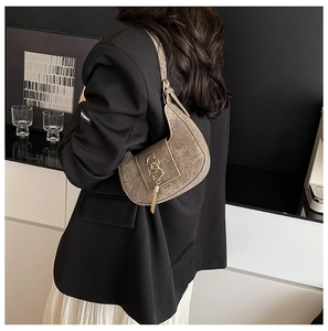 Detail of vintage brown crescent hobo bag with gold logo and tassel on a model