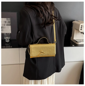 Detail of metallic gold woven baguette bag showing intricate texture and knot clasp