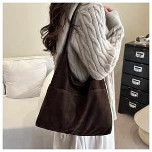 Detail der dunkelbraunen Wildleder-Schultertasche mit zwei Außentaschen am Lifestyle-Modell