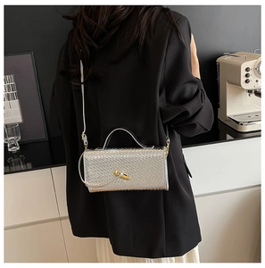 Silver woven shoulder bag with golden bamboo lock shown in a stylish lifestyle setting