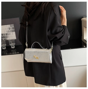 Silver woven texture shoulder bag with gold twist lock worn by a model in lifestyle setting