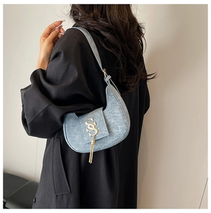 Close-up of light blue crescent shoulder bag with golden S-letter and fringe detail