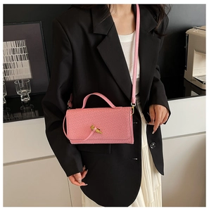 Pink quilted shoulder bag with gold twist lock shown on a model in a black blazer