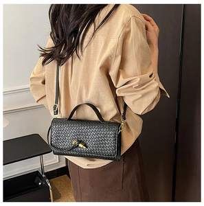 Detail shot of black woven leather bag on person showing size and shoulder strap drop