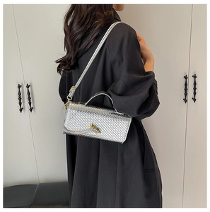 Detail of silver woven texture crossbody bag with gold-tone knot twist lock closure