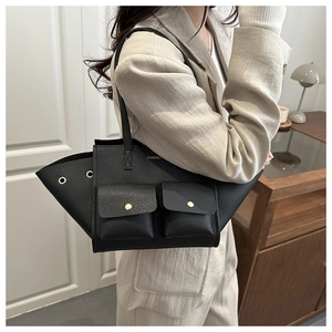 Detail of black pebbled leather tote bag with wing design and gold hardware pockets