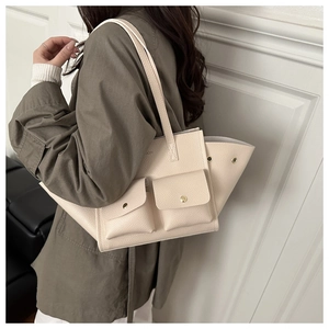 Détail du sac cabas beige en cuir grainé avec deux poches frontales à rabat magnétique