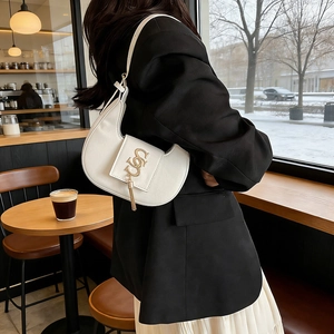 White faux leather dumpling-style shoulder bag with gold logo and long tassel pendant
