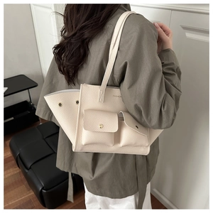 Détail du cabas en cuir grainé blanc cassé avec boutons pression dorés et lettrage
