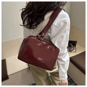 Détail du sac cabas en cuir verni rouge foncé avec anneaux en métal argenté et logo
