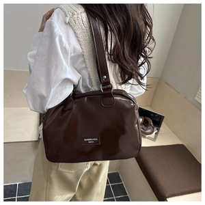 Vue détaillée du grand sac Boston en cuir brillant marron foncé avec logo et accessoires