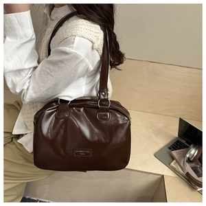 Détails de la texture du cuir marron foncé et finitions argentées du sac Boston