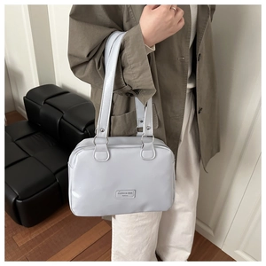 Gros plan d'un sac Boston lilas avec détails argentés porté par un mannequin