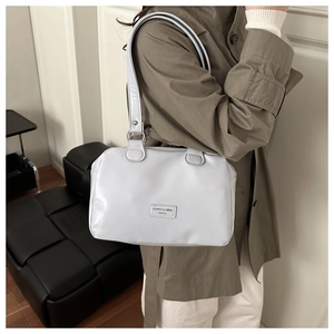 Gros plan du sac sous le bras en cuir blanc avec le logo métallique CAHRES & HEKA