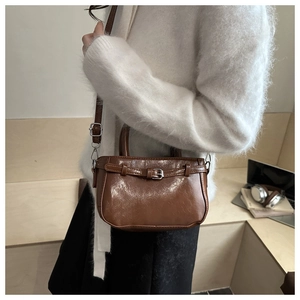 Detail of brown vintage crossbody bag with glossy PU leather and silver buckle strap
