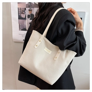Detail of cream corduroy tote bag with golden rivets and fashion brand label texture