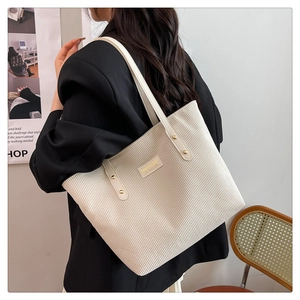 Detail of off-white corduroy tote bag with vertical texture and gold fashion logo