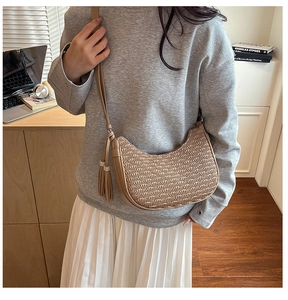 Detail of khaki pleated crescent bag featuring long tassels and slim leather shoulder strap