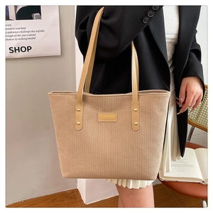Close-up of beige corduroy tote bag with leather straps and golden metal rivets