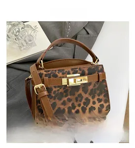Detailed close-up of leopard print handbag with brown leather strap and gold metal lock