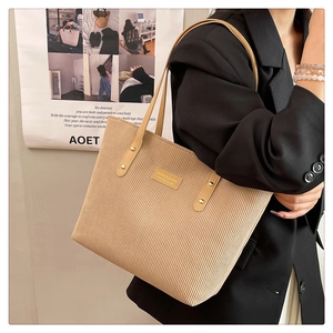 Close-up of beige corduroy tote bag showing vertical texture and brown faux leather straps