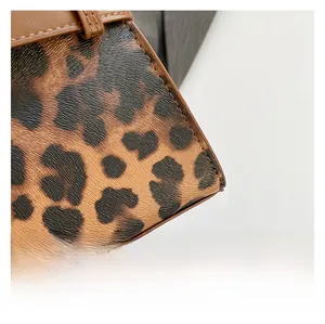 Close-up of leopard print fabric texture and brown leather edge detailing on crossbody bag