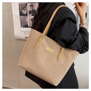 Detail view of the khaki corduroy tote bag worn over the shoulder by a model