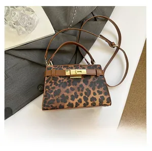 Leopard print handbag with gold clasp and leather trim shown next to a smartphone