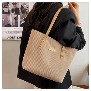 Detailed close-up of khaki corduroy tote bag featuring metal rivets and side label
