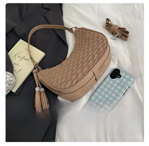 Detail of pleated crescent shoulder bag in light coffee with decorative tassel accents