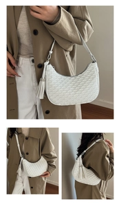 Detailed view of white quilted crescent moon shoulder bag with sparkling tassel pendant