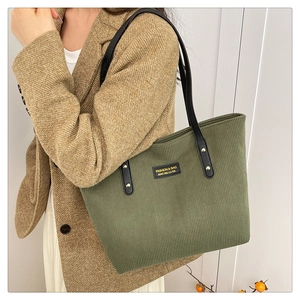 Detailed texture of olive green corduroy tote bag with black leather straps and rivets