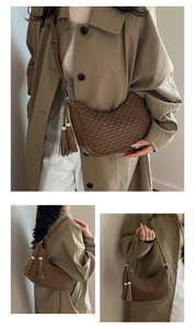 Detail of caramel crescent shoulder bag featuring scalloped pleats and tassel charm