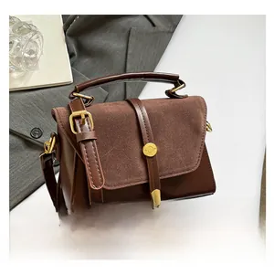 Détail de la texture mixte entre cuir lisse marron et daim mat sur ce sac à bandoulière