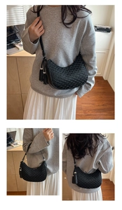 Detail showing the wave-woven texture and tassel charms of this black crescent bag