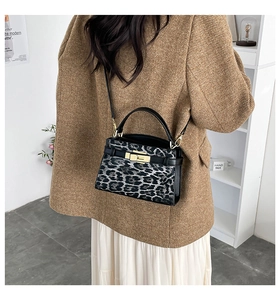 Detailed view of leopard print crossbody bag with golden hardware and leather strap