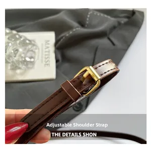 Gros plan sur une bandoulière réglable en cuir marron foncé avec boucle en métal doré chic