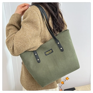 Detail view of large corduroy tote bag in olive green with leather straps and gold rivets