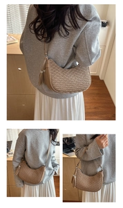 Detail of beige crescent shoulder bag featuring pleated texture and twin tassels