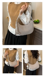 Detail of light grey half-moon bag featuring shell embossing and elegant long tassel charm