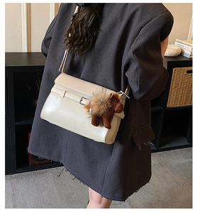 Detail of cream white PU leather shoulder bag with a brown plush horse charm