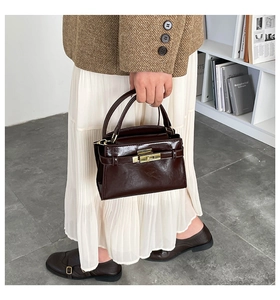 Détail d'un sac à main en cuir marron foncé avec fermoir doré et finition vintage